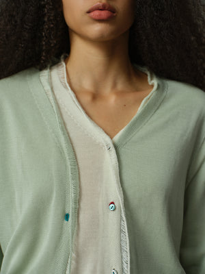 Close-up of a person wearing a light green cardigan with a blurred background