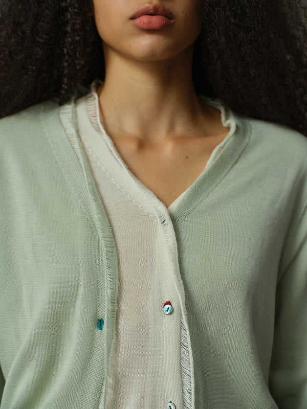 Close-up of a person wearing a light green cardigan with a blurred background