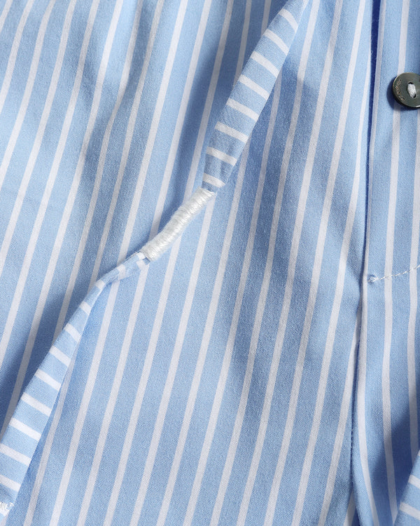 Close-up of a light blue and white vertically striped shirt fabric, showing the collar, button, and a folded section of the lining.