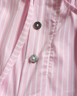 Close-up of a pink and white vertically striped button-up shirt showing the fabric texture and two dark metal buttons.