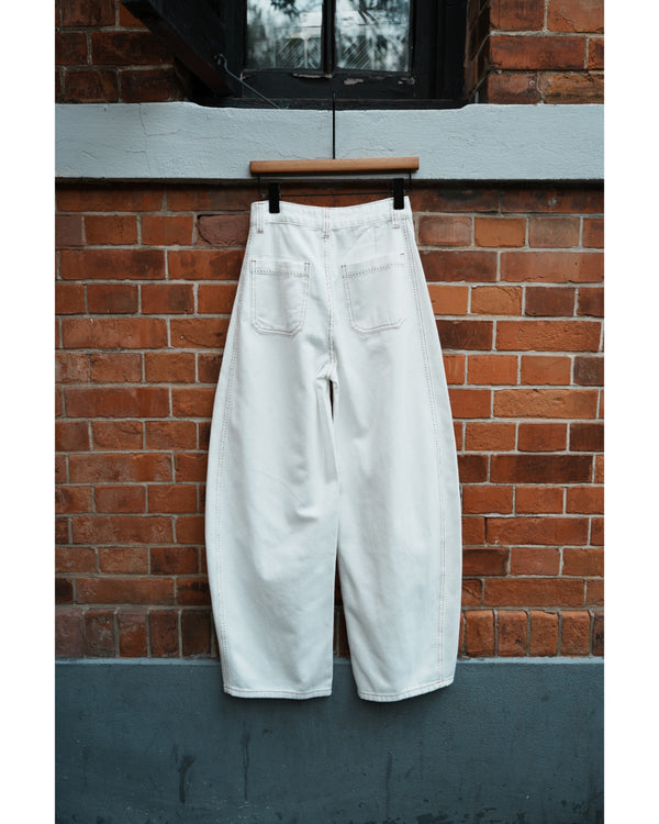 White pants hanging on a hook against a brick wall.
