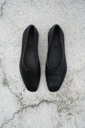 Pair of black flats on a textured concrete surface