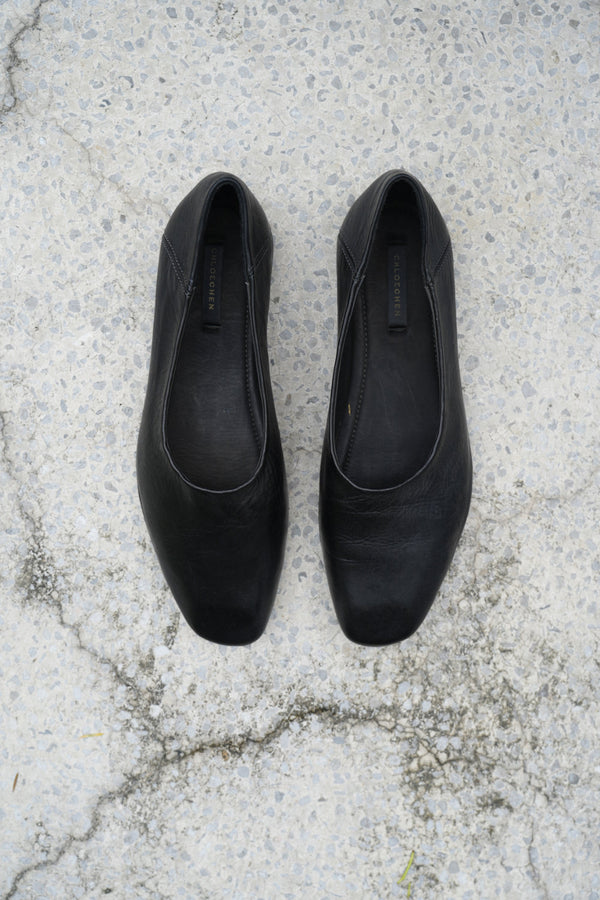 Pair of black flats on a textured concrete surface