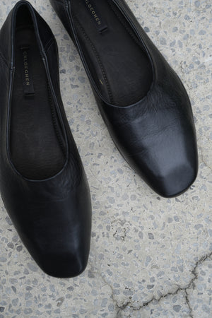 Pair of black leather shoes on a textured concrete surface