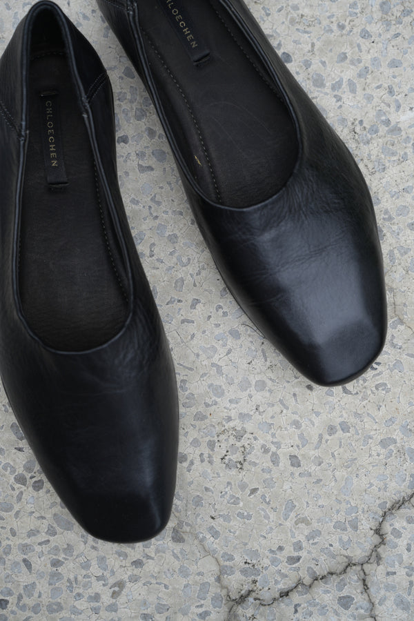 Pair of black leather shoes on a textured concrete surface