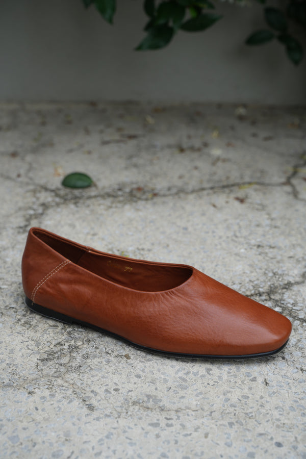 A brown leather shoe on a textured concrete surface