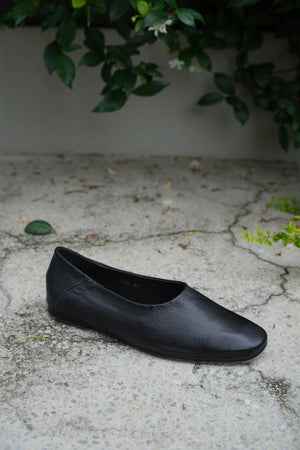 A black leather shoe on a textured concrete surface