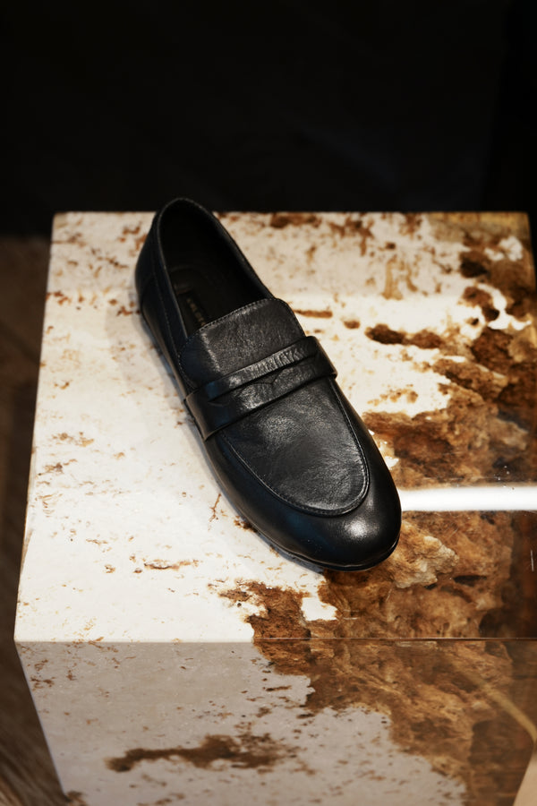 Black loafer shoe on a textured surface