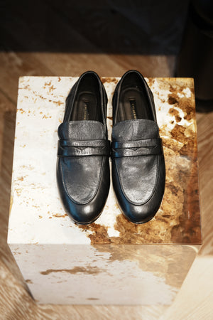 Pair of black loafers on a rustic wooden block
