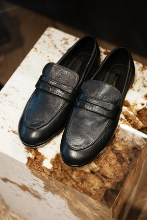 Pair of black loafers on a rustic wooden block