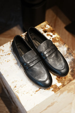 Pair of black loafers on a rustic wooden block