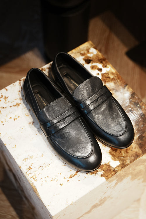 Pair of black loafers on a rustic wooden block