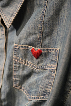 close up of a cropped denim jacket with heart embroidery on chest pocket