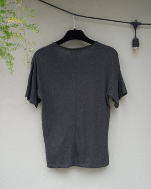 back of a  gray sweater on a light surface with a plant in the corner