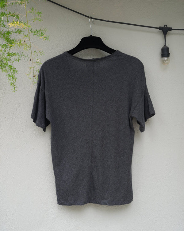 back of a  gray sweater on a light surface with a plant in the corner