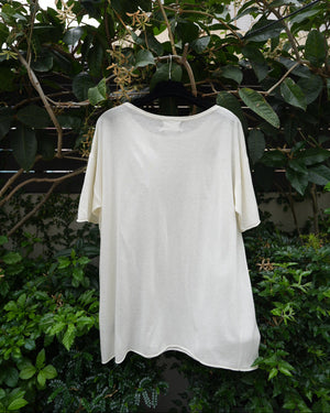 back of a white top with braided neckline hanging on the tree