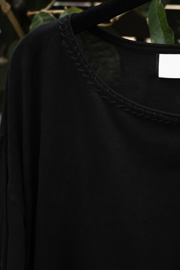 close up of a black top with braided neckline hanging on the tree
