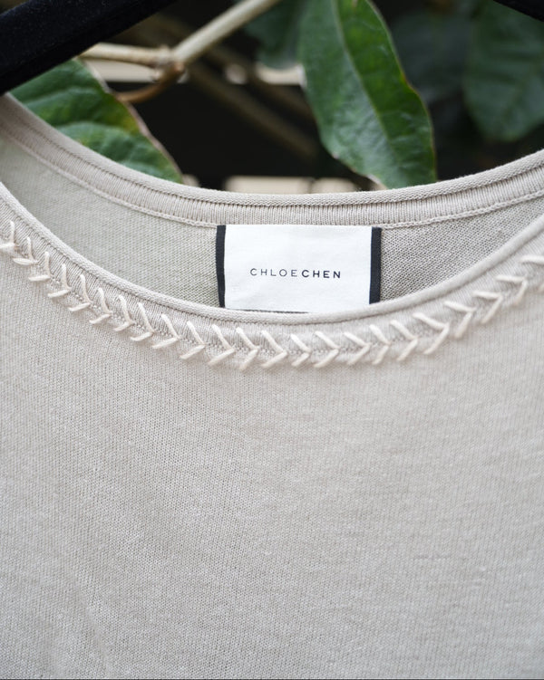 close up of a grey top with braided neckline 