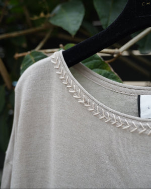 close uo of a grey too with braided neckline 
