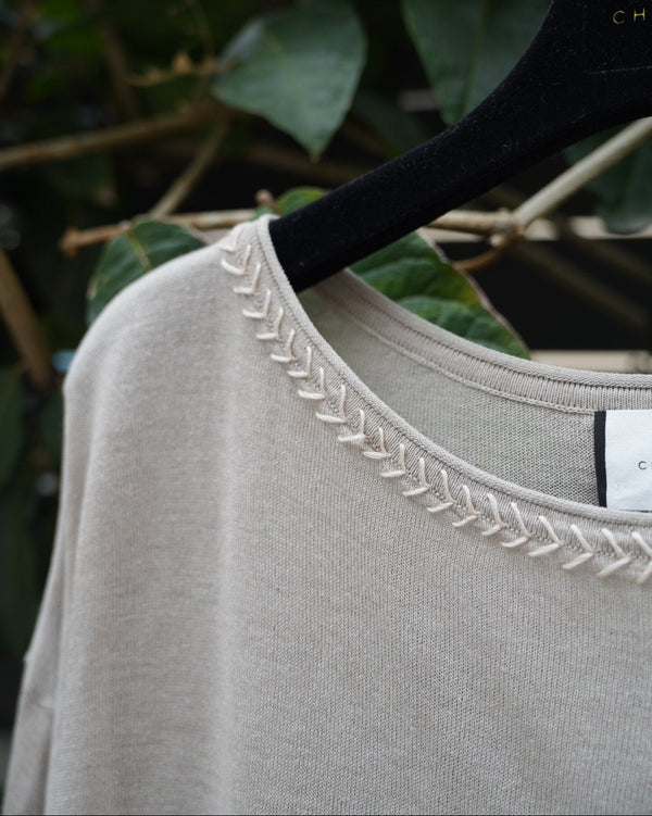 close uo of a grey too with braided neckline 