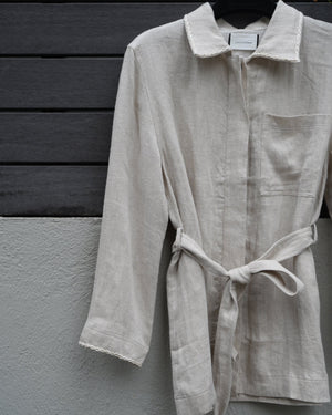 Light-colored jacket hanging on a dark wooden door against a gray wall