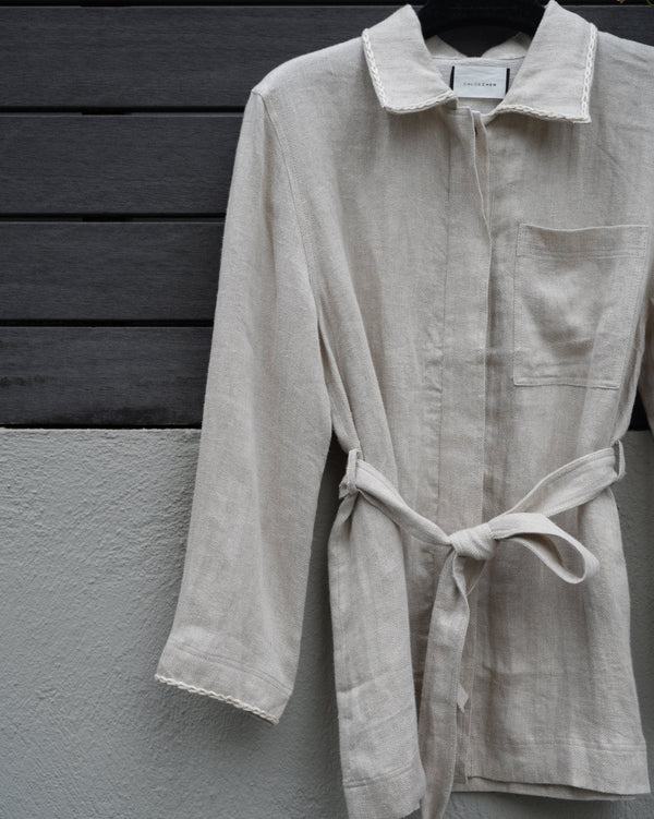 Light-colored jacket hanging on a dark wooden door against a gray wall