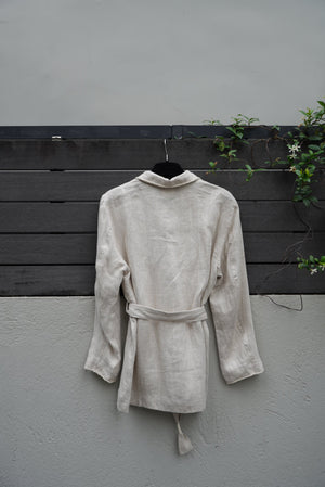 back of a Light-colored jacket on a dark wooden door with a gray wall background