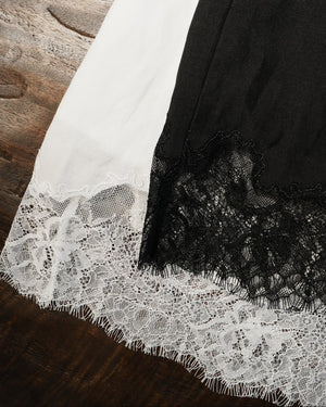 Close-up of a black garment with white lace trim on a wooden surface