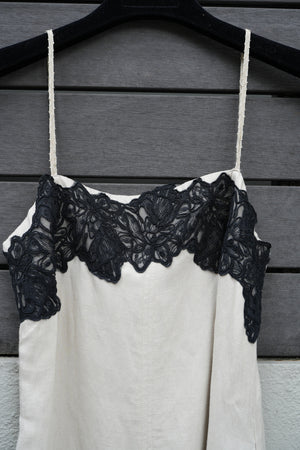 Close-up of a black lace trim on a beige garment against a wooden background