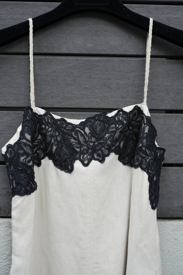 Close-up of a black lace trim on a beige garment against a wooden background
