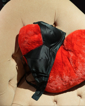 black bra on a red heart shaped cushion against a pink sofa