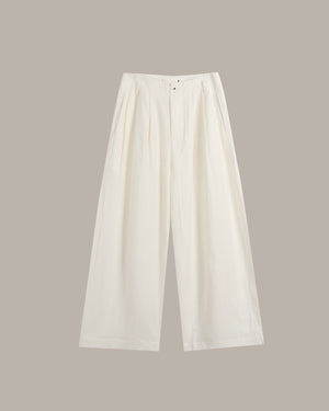 A pair of off-white wide-leg cropped trousers with pleated detailing at the front waist, displayed flat against a solid taupe background.