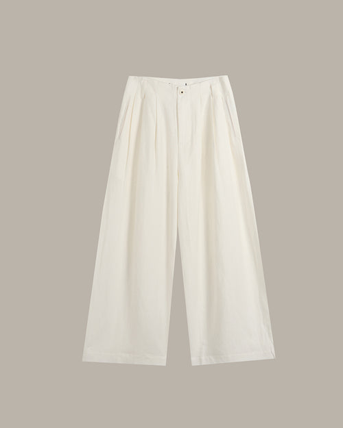 A pair of off-white wide-leg cropped trousers with pleated detailing at the front waist, displayed flat against a solid taupe background.