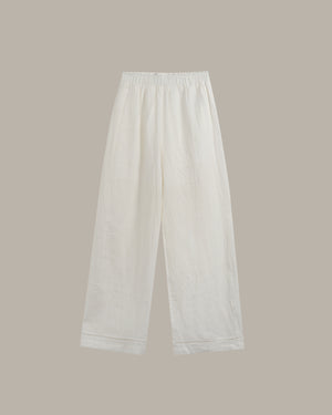 White wide-leg cropped pants with an elastic waistband, shown flat against a solid taupe background.
