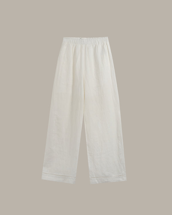 White wide-leg cropped pants with an elastic waistband, shown flat against a solid taupe background.