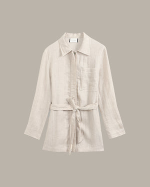 linen jacket against a dark background with a plant.