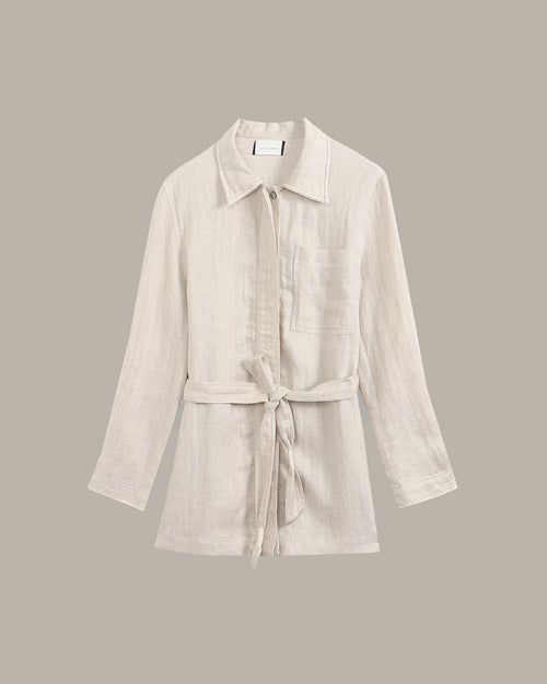 linen jacket against a dark background with a plant.