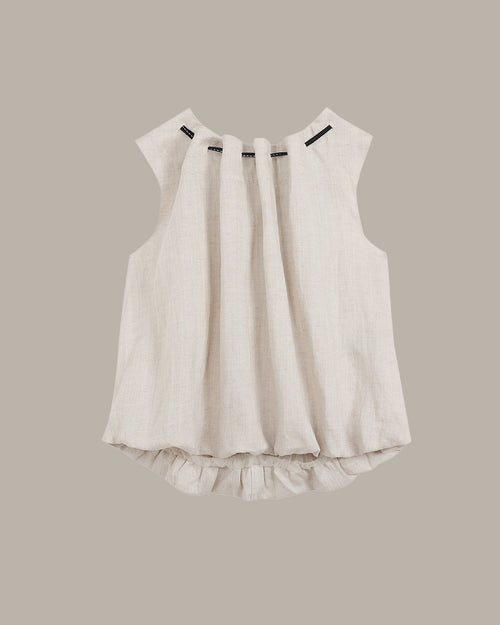 White sleeveless top with ruffled hem on a beige background