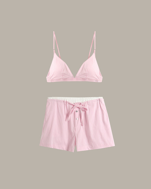 A two-piece pink lounge set featuring a thin-strap triangle top and matching drawstring shorts with a white inner lining, displayed against a solid taupe background.
