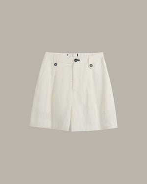 A pair of off-white pleated shorts with button details on the waist, displayed flat against a solid taupe background.