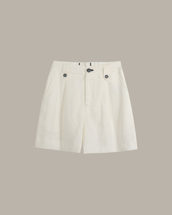 A pair of off-white pleated shorts with button details on the waist, displayed flat against a solid taupe background.