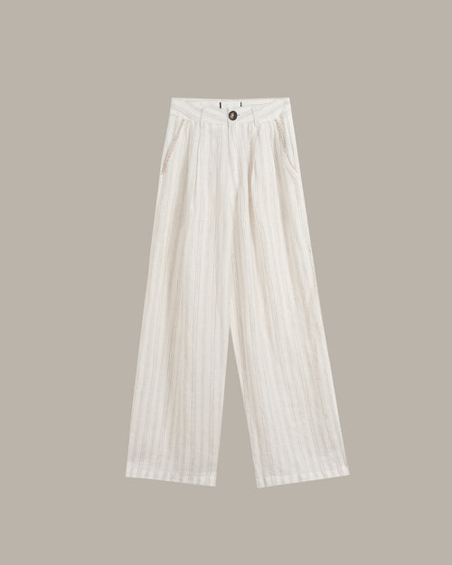 White wide-leg trousers with a subtle vertical textured stripe pattern, featuring a high-waisted design and front button closure, shown against a solid taupe background.