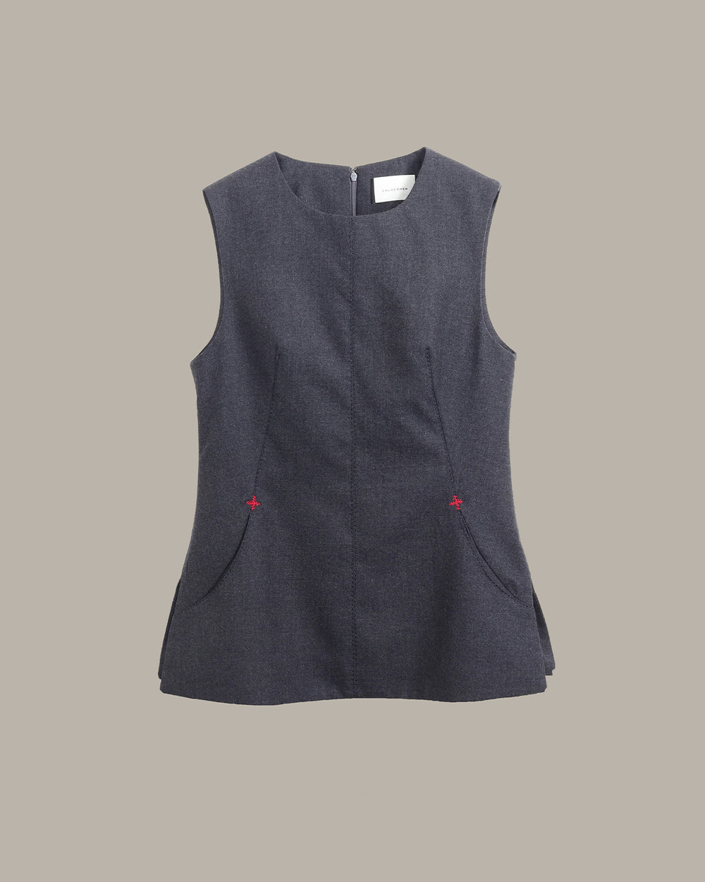 A sleeveless dark gray textured vest with a round neckline, front pockets, and small red embroidered star details on the sides, shown against a solid beige background.