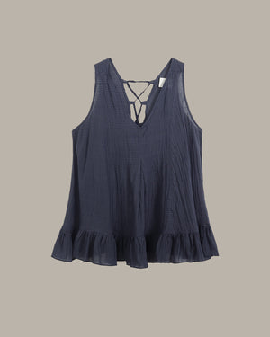 Navy blue sleeveless top with ruffled hem on a beige background