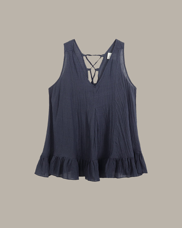 Navy blue sleeveless top with ruffled hem on a beige background