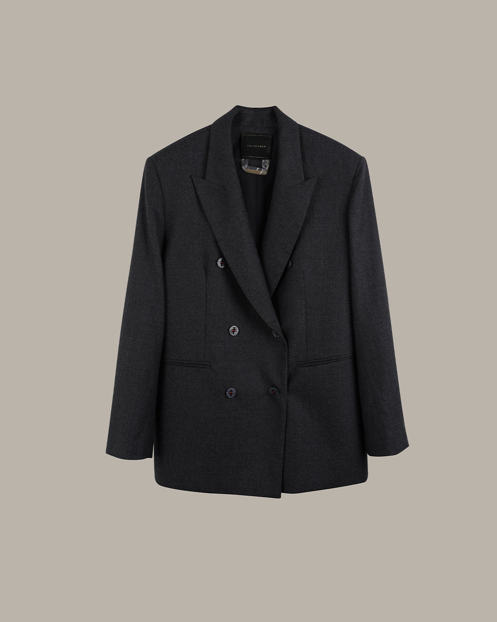 A dark charcoal gray double-breasted blazer with notched lapels and a subtle textured weave, displayed against a solid warm gray background.