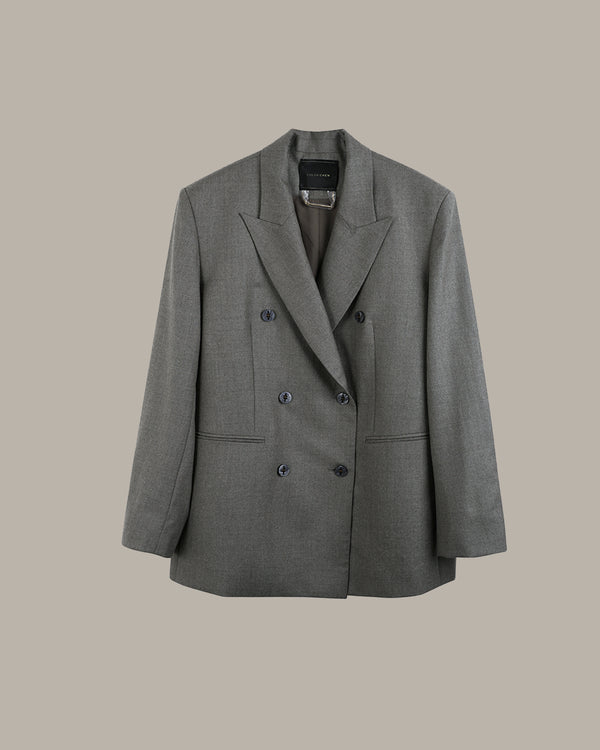 A gray double-breasted blazer with notched lapels and dark buttons, displayed against a solid beige background.