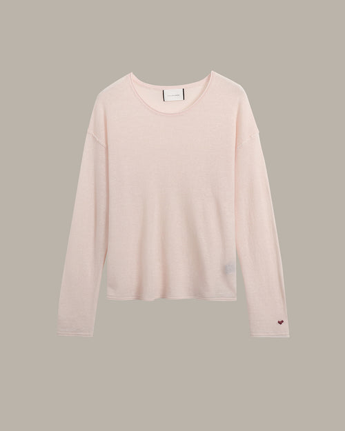 A pale blush pink long-sleeve crewneck knit top, shown flat against a solid taupe-gray background.