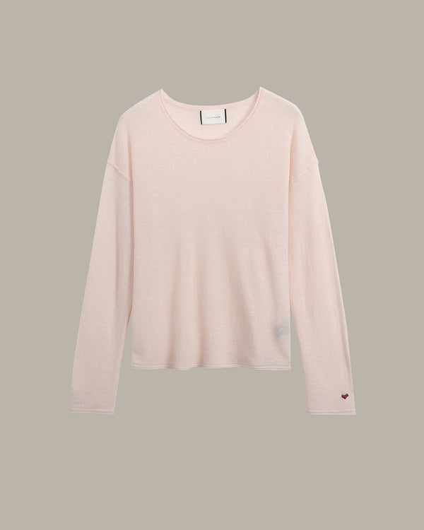A pale blush pink long-sleeve crewneck knit top, shown flat against a solid taupe-gray background.