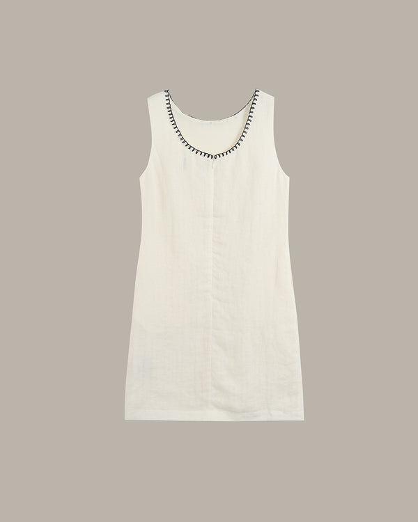 White sleeveless dress with decorative neckline on a beige background